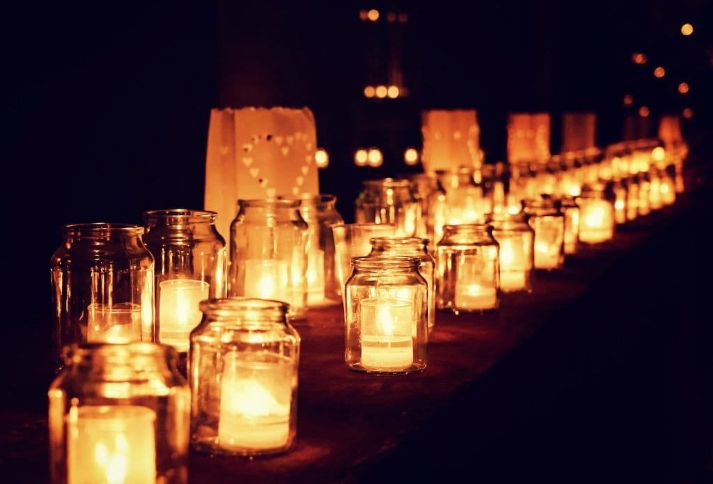 Goup of glass jars with burning candles on the dark background, selective focus. Advent, overwhelm, calm, time.